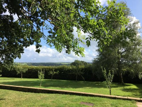a garden with trees and green grass and a fence at East Hillerton House in Crediton