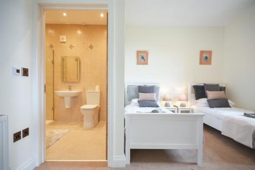 1 dormitorio con 2 camas y baño con lavamanos en Countryside Escape - The Night Owl, en Alnwick