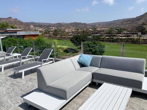 a couch and chairs on a patio with a golf course at Suecia Villa Opal Anfi Tauro in Mogán