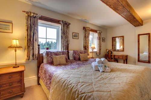 a bedroom with a large bed with two teddy bears on it at Middlehead Cottages in Pickering