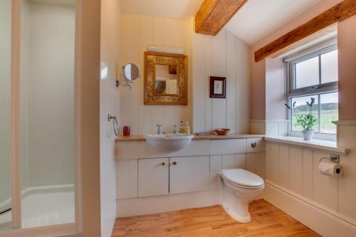 a bathroom with a toilet and a sink and a window at Middlehead Cottages in Pickering