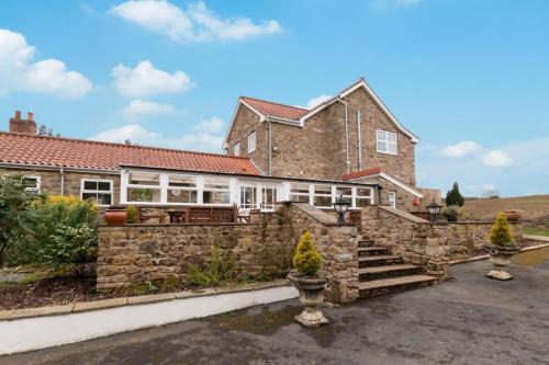 a large brick house with a stone wall at Middlehead Cottages in Pickering