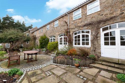 a brick house with a patio and a table at Middlehead Cottages in Pickering