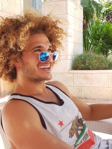 a man wearing sunglasses and a tank top at Mike's House Jerusalem in Jerusalem