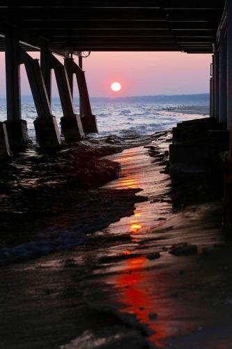a sunset from under a pier on the beach at Apartment Neptun in Ueckeritz