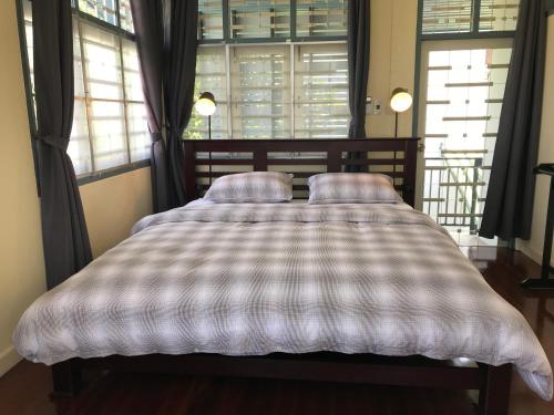 a bed with two pillows in a room with windows at Ban Soi San Sook Homestay in Songkhla