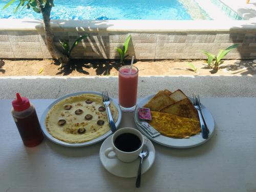 a table with a plate of pancakes and a cup of coffee at Villa PhyPhy 3 in Gili Trawangan