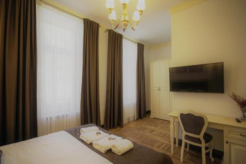 Habitación de hotel con cama, escritorio y TV. en La Curtea Domneasca en Piatra Neamţ