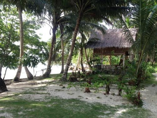 une cabane avec des palmiers sur la plage dans l'établissement Masokut Surf Camp Siberut Mentawai front wave,E-Bay,Beng-Bengs,Pitstops ,Bank Vaults,Nipussi, à Masokut