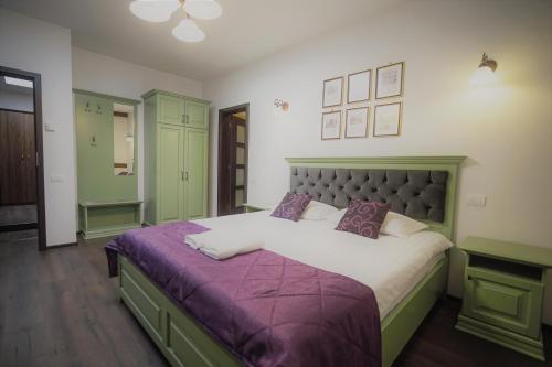 a bedroom with a large bed with a purple blanket at La Curtea Domneasca in Piatra Neamţ
