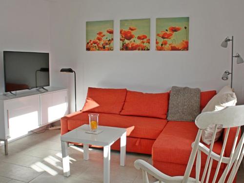 een woonkamer met een rode bank en een tafel bij Ferienhaus Domizil Wattenmeer in Friedrichskoog