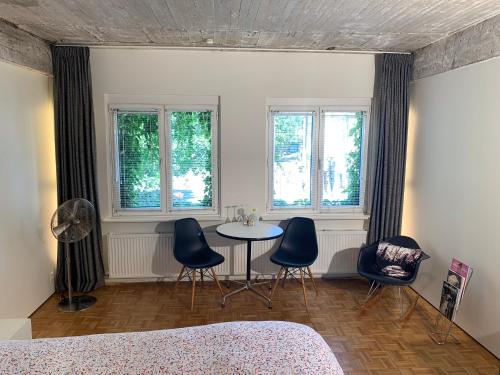 a bedroom with a table and chairs and windows at B&B Yellow Submarine in Antwerp