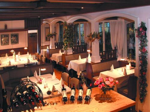 un restaurante con mesas blancas, sillas y flores en Hotel Die Post, en Offenbach