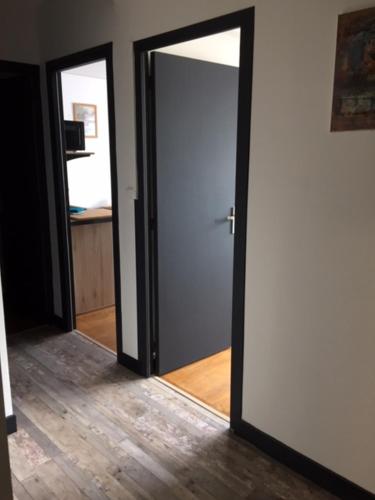 un couloir avec une porte ouverte et un miroir dans l'établissement Basilique/carmel tout confort, à Lisieux
