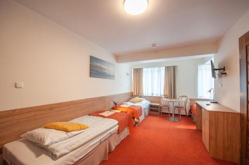 a hotel room with two beds and a desk at Pomorze Ustka in Ustka