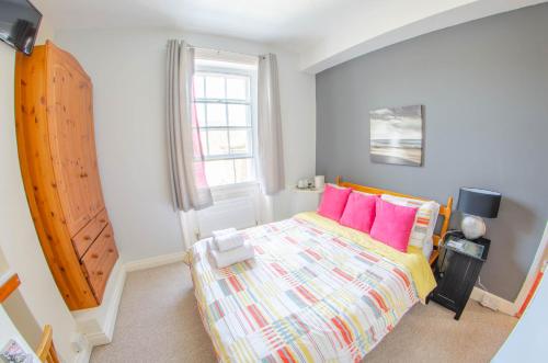 a bedroom with a bed with colorful pillows and a window at Olivers Guest House in Weymouth