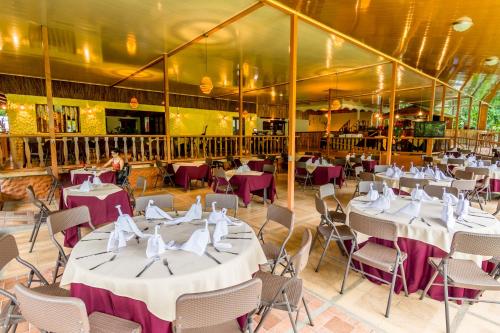 a dining room with white tables and chairs at Ara Ambigua Lodge in Sarapiquí