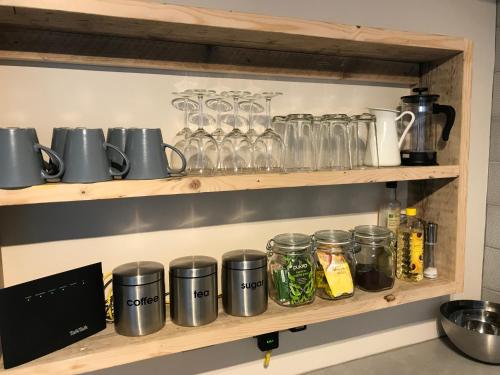 a shelf with glasses and jars on it at 2 Crown Barton in Glastonbury