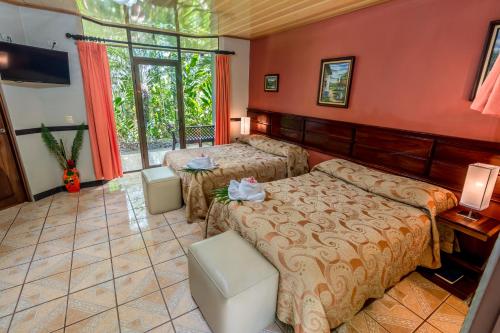 a hotel room with two beds and a television at Ara Ambigua Lodge in Sarapiquí