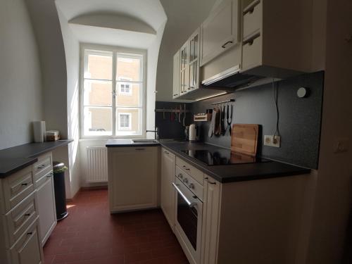 a kitchen with white cabinets and black counter tops at Stadthotel - Das alte Gefängnis in Braunau am Inn