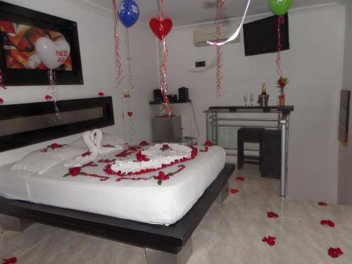 a bedroom with a bed with red flowers and balloons at Torettos in Yumbo