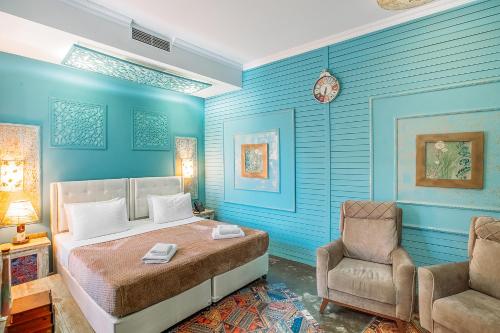 a bedroom with blue walls and a bed and a chair at Hotel Aivani Old Tbilisi in Tbilisi City