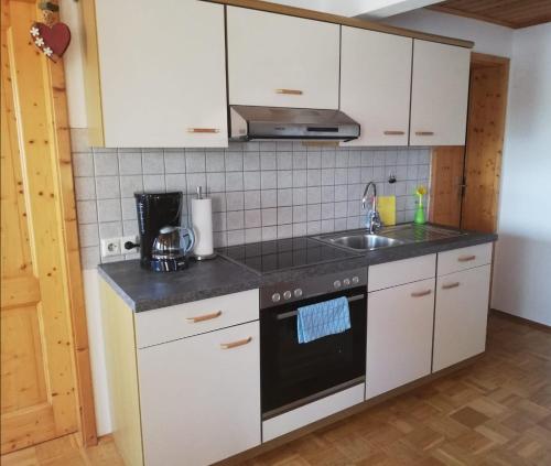 uma cozinha com armários brancos e um forno de fogão preto em Ferienhof Jungkunz em Schwarzenbach am Wald