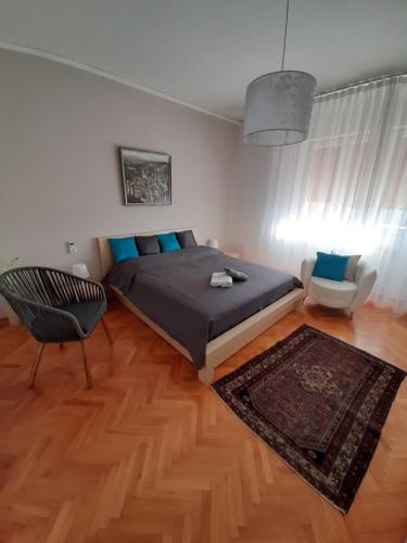 ein Schlafzimmer mit einem Bett, einem Stuhl und einem Teppich in der Unterkunft FUSNAR in Aquilinia