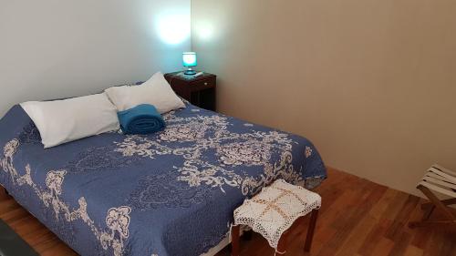 1 dormitorio con 1 cama con manta azul y silla en Antigua Fonda Duplex Studio en Concepción del Uruguay