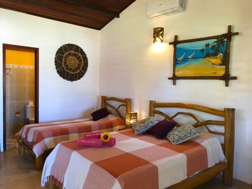 a bedroom with two beds and a picture on the wall at Hotel Pousada Beleza das Ondas in Cumbuco
