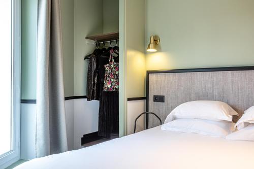 a bedroom with a white bed and a closet at Hotel de l'Aqueduc in Paris