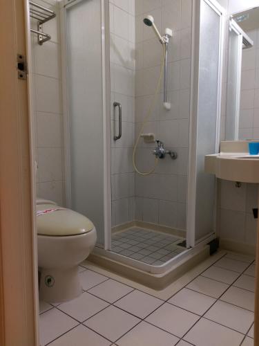 a bathroom with a shower and a toilet and a sink at 85 Cape Inn in Kaohsiung