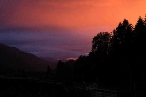 a sunset in the mountains with trees in the foreground at Riversong Centre Thermal in Les Plans-sur-Bex