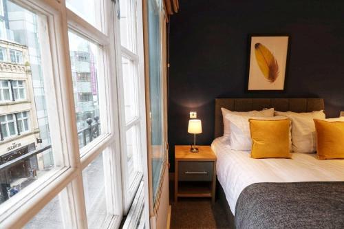 - une chambre avec un lit doté d'oreillers jaunes et d'une fenêtre dans l'établissement Heart of Leeds City Centre Living - Sleeps 6, à Leeds