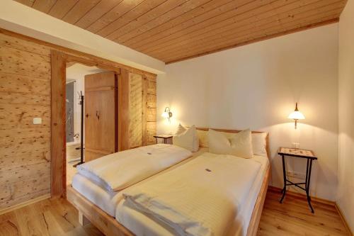 ein großes Bett in einem Zimmer mit Holzdecke in der Unterkunft Zum Kirchenbauer in Oberammergau