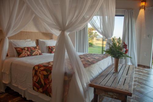 a bedroom with a bed with a table and a window at Fazenda do Rosa in Praia do Rosa