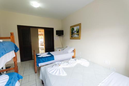 a room with two beds and a television in it at Hotel Naturalis in Paranaguá