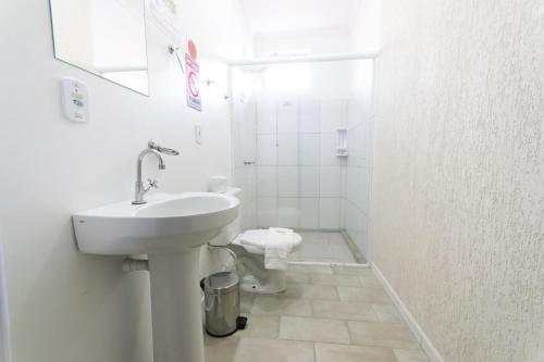 a white bathroom with a sink and a toilet at Hotel Naturalis in Paranaguá