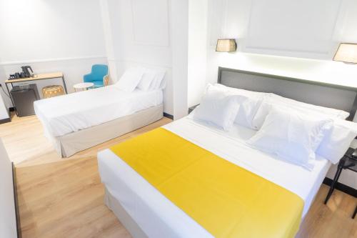 a bedroom with two beds with white and yellow at Hotel Boutique Puerta de las Granadas in Granada