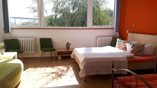 a bedroom with two beds and two chairs and two windows at Hostel Stralsund in Stralsund