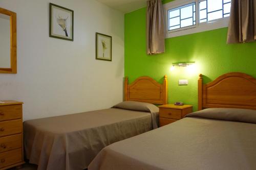 1 dormitorio con 2 camas y pared verde en Apartamentos Ecuador en Playa del Inglés