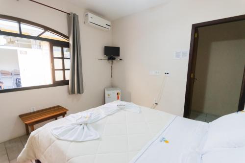 a bedroom with a large white bed and a window at Hotel Naturalis in Paranaguá