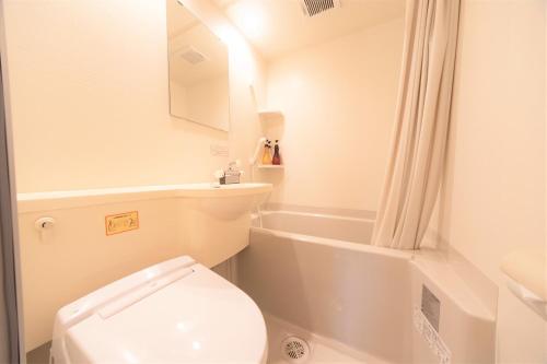 a white bathroom with a toilet and a bath tub at Kagura White Horse Inn in Yuzawa