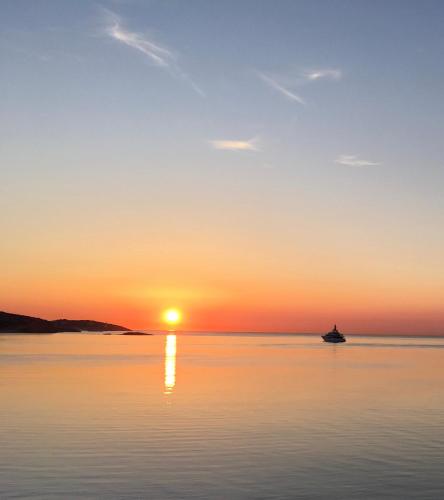 a sunset on the water with a boat in the distance at Enkala Apartamentos in Ibiza Town