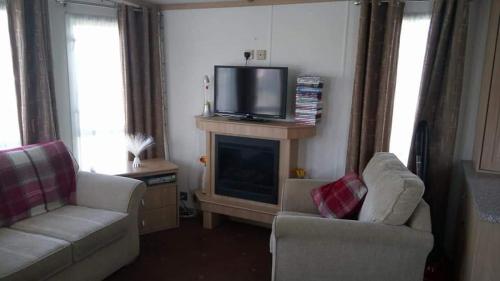 a living room with two chairs and a television on a fireplace at ChapmanHolidayLets Cayton Bay in Cayton