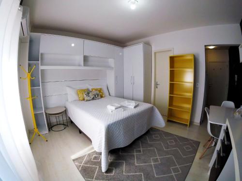 um quarto com uma cama branca e um armário amarelo em Studio Central XV Master Collection em Passo Fundo