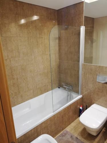 a bathroom with a tub and a toilet and a sink at Beach Sea View Apartment in Setúbal