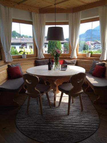 a dining room with a table and chairs and windows at Apartment Hahnenkammblick in Reith bei Kitzbühel