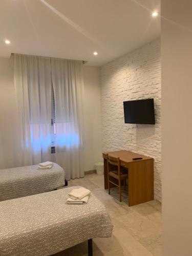 a room with two beds and a table and a television at Bologna Centrale Stanze in Bologna