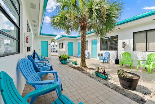 a patio with blue chairs and a palm tree at Hollywood Beachside Boutique Suite in Hollywood